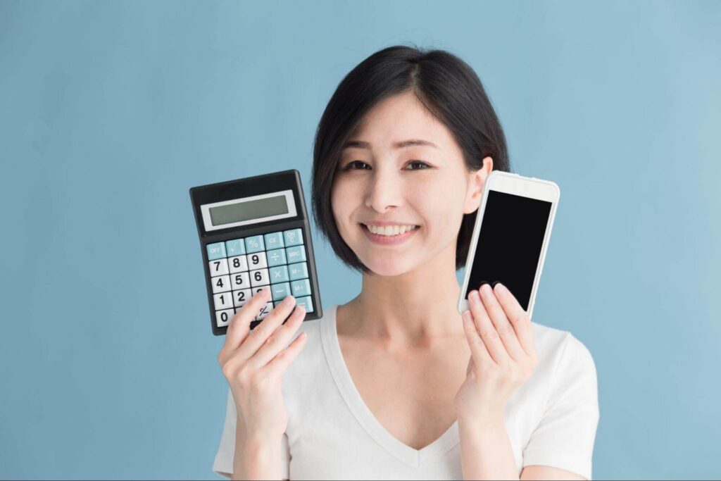 スマホと電卓を持つ笑顔の女性