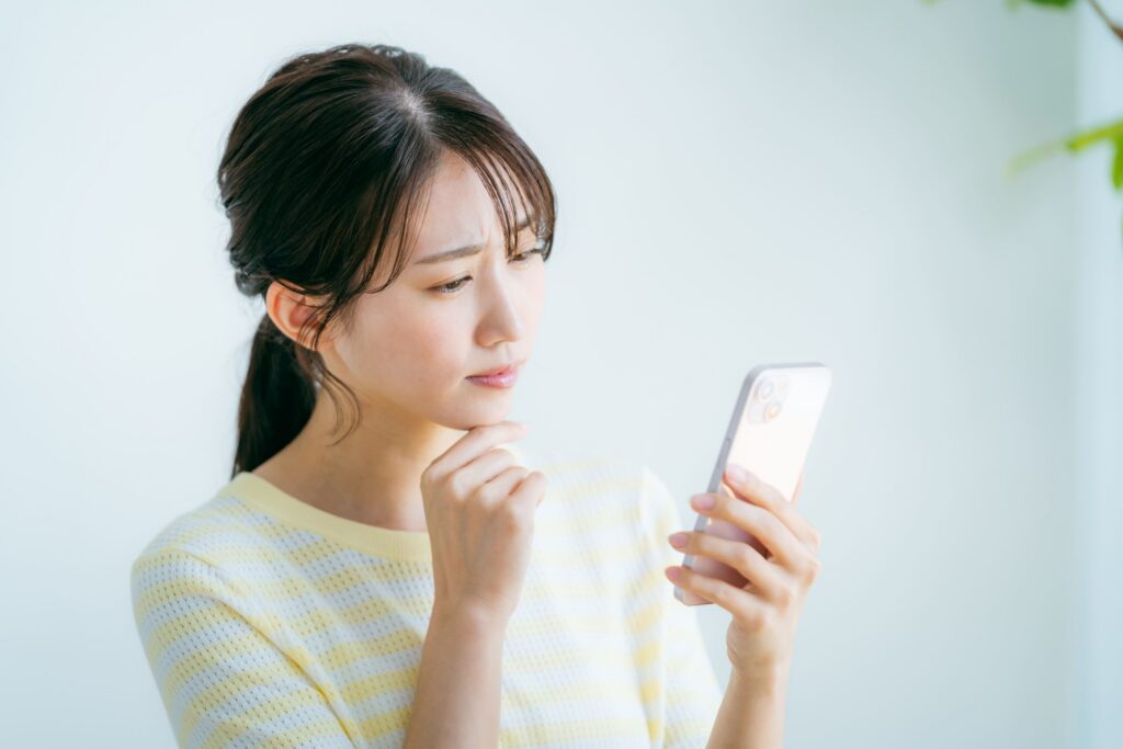 スマホを見て悩む女性