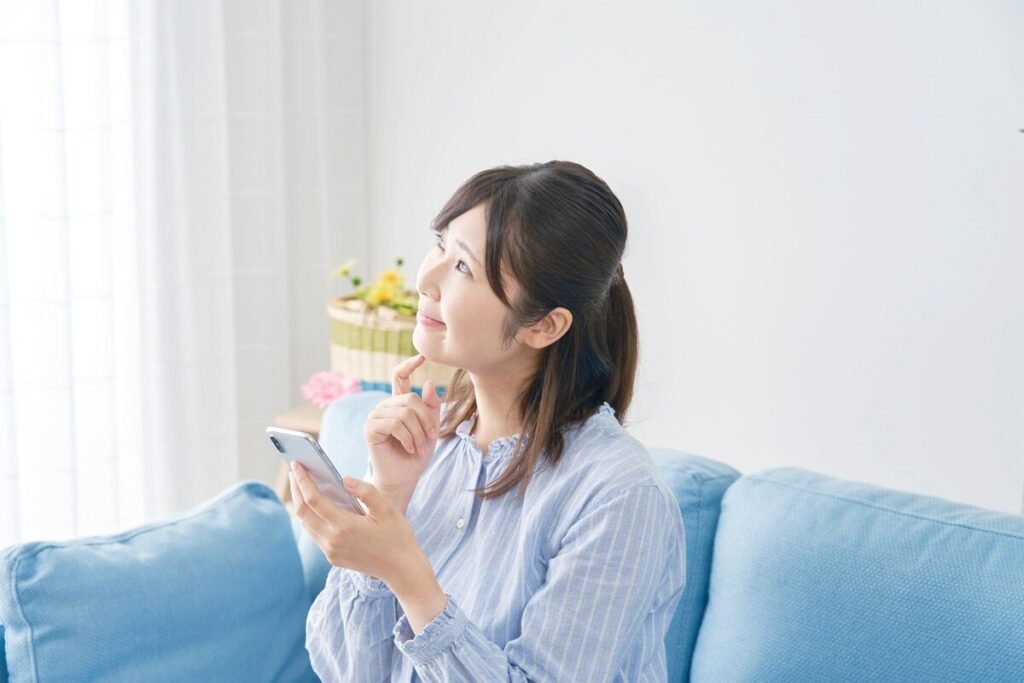 ソファに座りながらスマホを持っている女性
