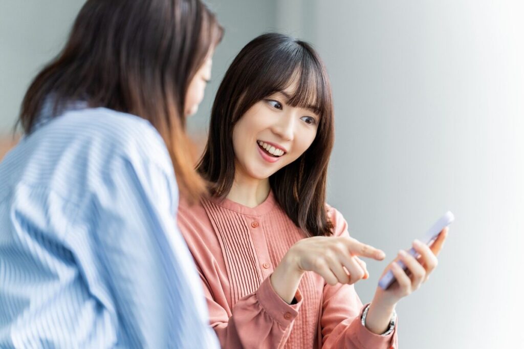 スマホの画面を見る二人の女性