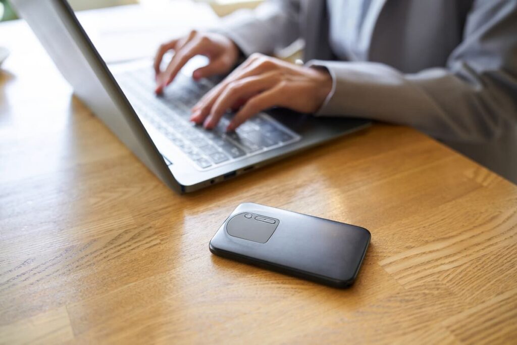 パソコンを操作する人と黒色のポケットWi-Fi