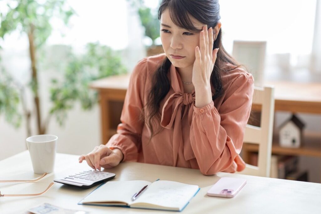 電卓を打ちながら悩む女性