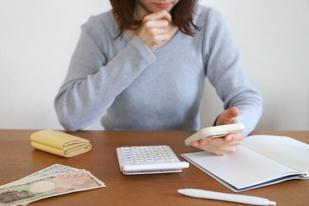 スマホを見ながらお金の計算をする女性